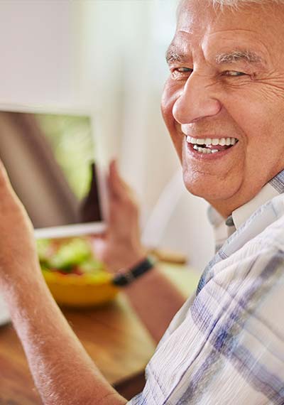 Modern senior man smiling while using tablet