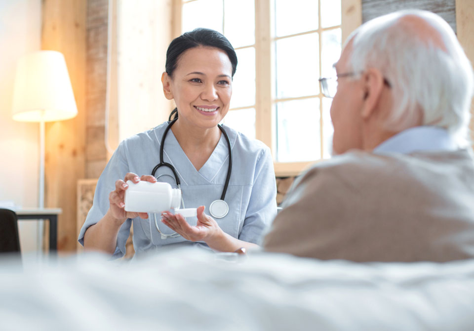 Nurse dispensing medication for a senior man